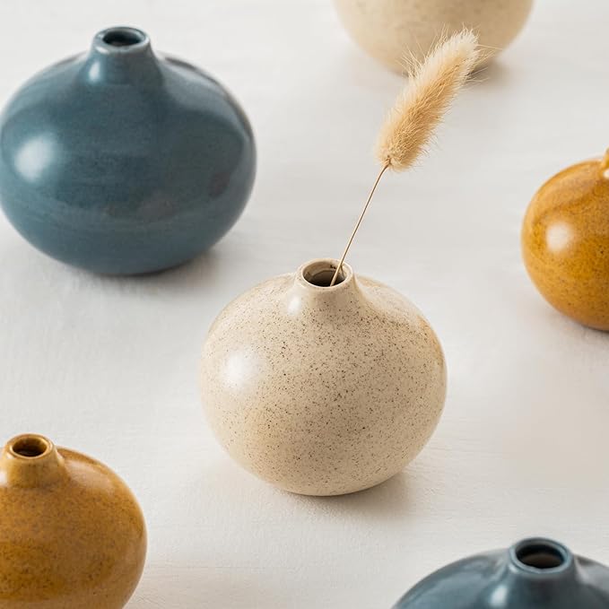 Mini ceramic bud vases close-up with stems: blue, cream speckled, and gold.