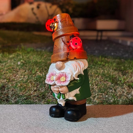 Solar garden gnome statue with brown hat, red ladybugs, green coat, holding pink flowers
