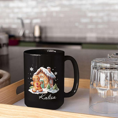 Black ceramic mug on table with gingerbread house graphic and “Kalisa” name.