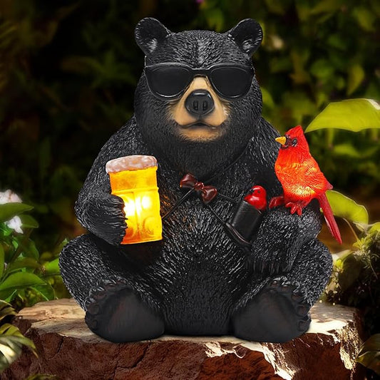 Black resin bear garden statue with sunglasses holding a glowing lantern and red cardinal