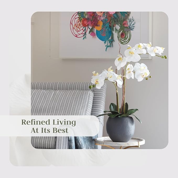 Faux white orchid double-stem in gray pot with green leaves on tabletop