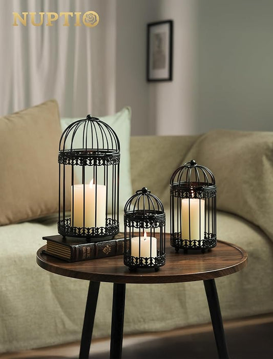 Three black metal birdcage candle lanterns displayed together on a small table