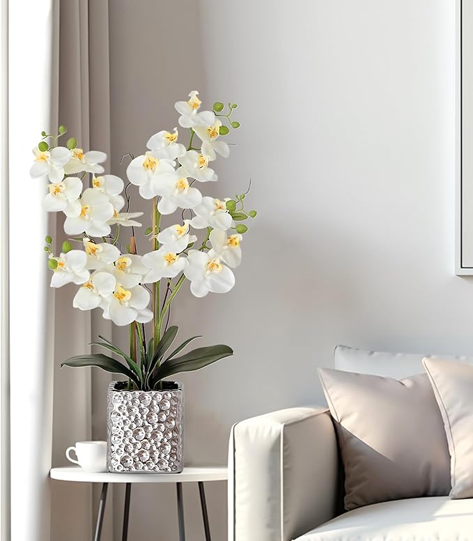 Faux white orchid arrangement in a silver textured vase on a side table