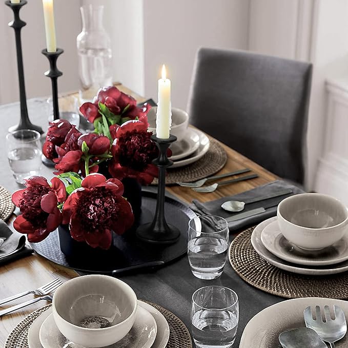 Black iron taper candle holder with a lit candle, slender fluted silhouette