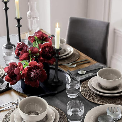 Black iron taper candle holder with a lit candle, slender fluted silhouette