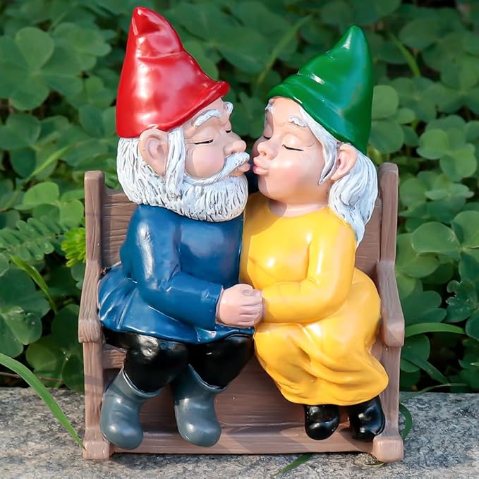 Garden gnome couple statue seated on wooden rocking chair, kissing, red and green hats