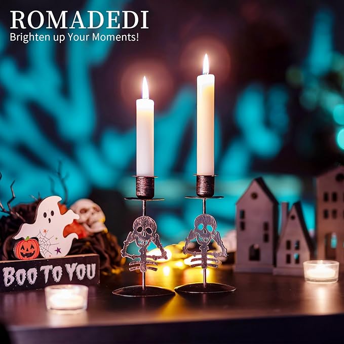 Two black skull gothic candle holders with lit taper candles
