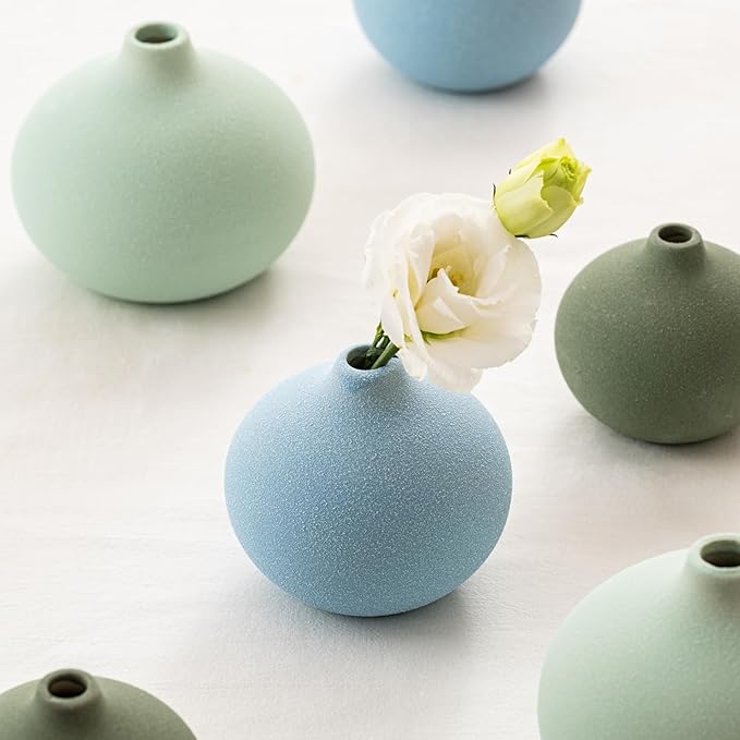 Close-up of three mini ceramic bud vases in mint, blue, and sage green with open necks