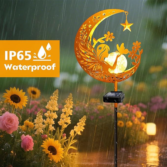 Orange crescent solar garden light with angel glass globe on stake, warm glow in rain.