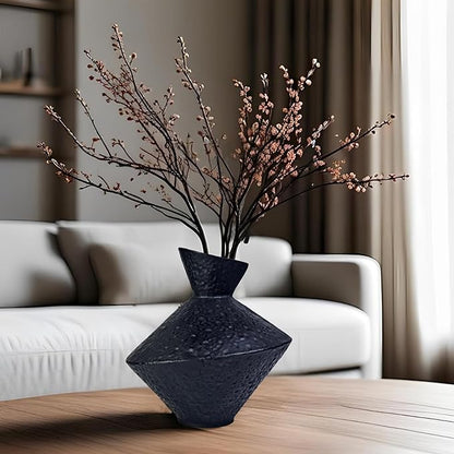 Dark hammered cast iron vase with angled neck holding pink flowering branches