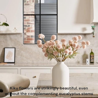 Beige faux pom-pom blooms and gold eucalyptus stems in a vase