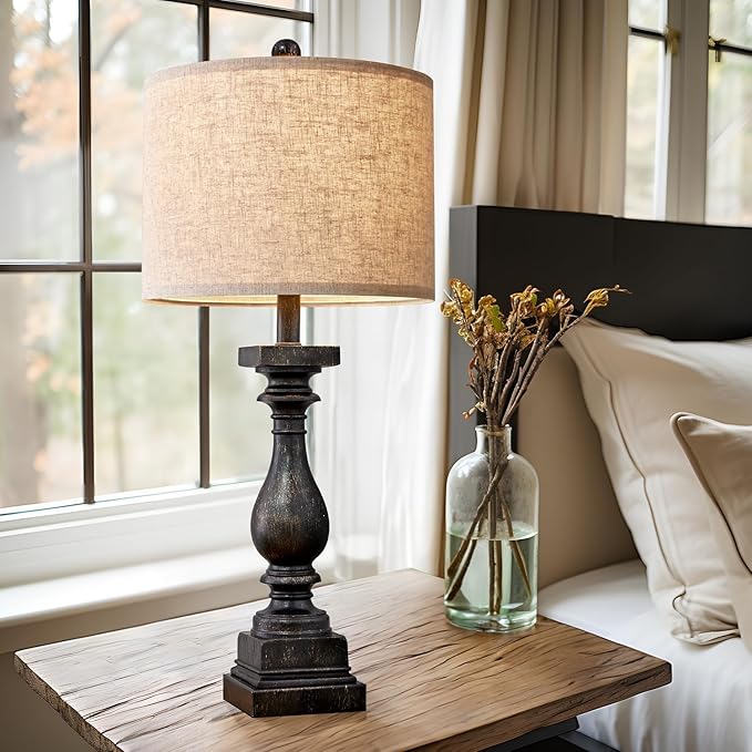 Fabric-shade table lamp with carved dark resin base on wooden side table