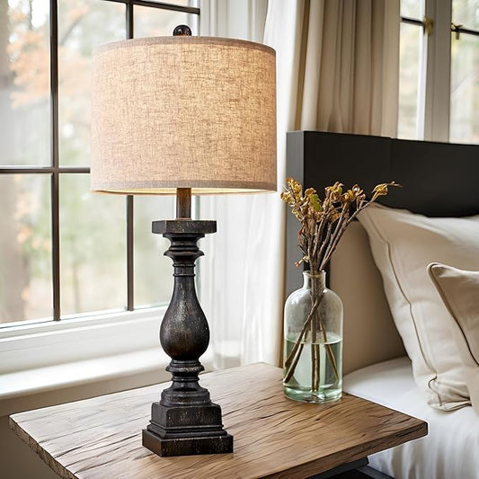 Fabric-shade table lamp with carved dark resin base on wooden side table