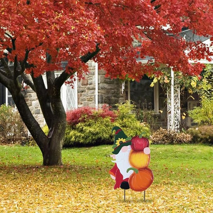 Metal gnome pumpkin stake decoration on yard, orange and red pumpkins with yellow glow accents