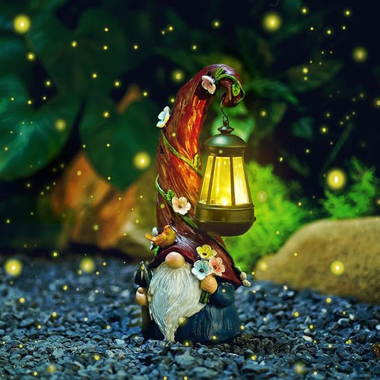 Solar gnome garden statue with glowing lantern, red hat and white beard on gravel