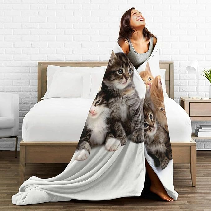 Cats throw blanket with kitten print draped over bed on white fleece