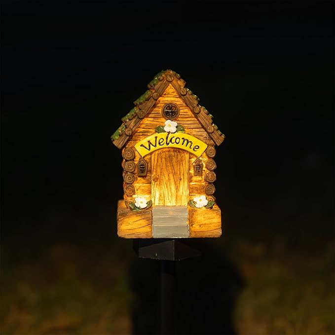 Glowing miniature wooden fairy cottage garden light with “Welcome” sign, on black stake.