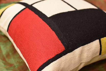 Geometric pillow cover close-up: red and black blocks with white lines on cream