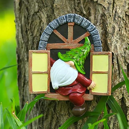 Garden gnome statue holding a green vine, white cap and red pants on a wooden window frame