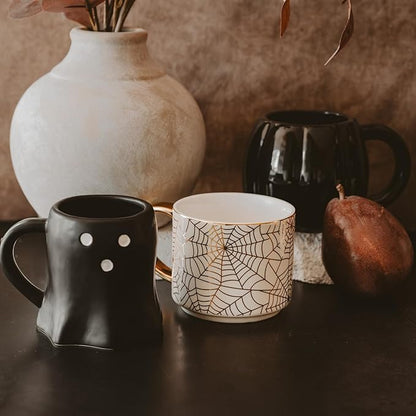 White spiderweb mug with gold handle and gold interior rim on tabletop