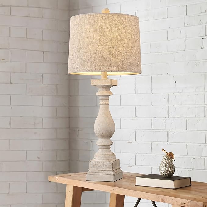 Beige fabric-shade farmhouse table lamp on wooden side table against white brick wall