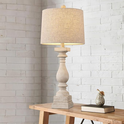 Beige fabric-shade farmhouse table lamp on wooden side table against white brick wall
