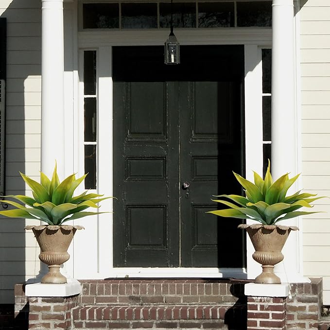 Two faux agave plants with yellow-green leaves in decorative urn planters