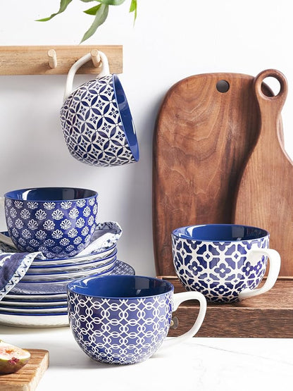 Blue-and-white patterned ceramic coffee mug with handle, shown among stacked mugs.