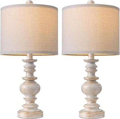 Close-up of two farmhouse table lamps with beige linen shades and whitewashed bases
