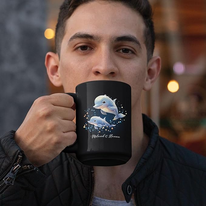 Black mug with blue dolphins swimming graphic and custom name, held by man