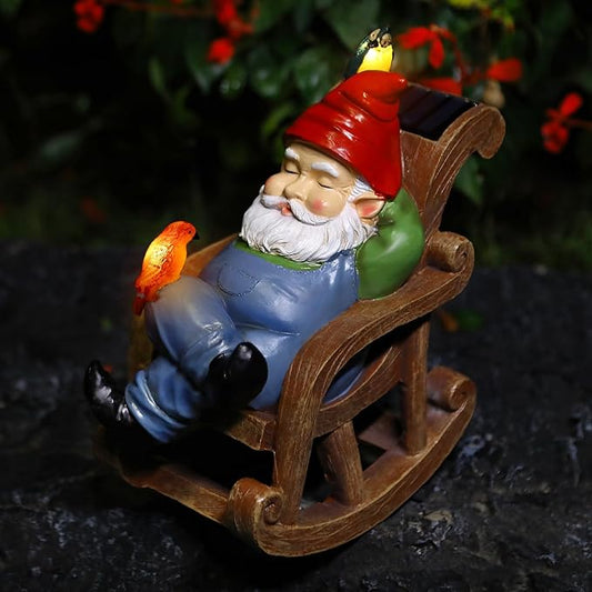 Solar gnome statue on brown rocking chair, red hat, green face, blue overalls