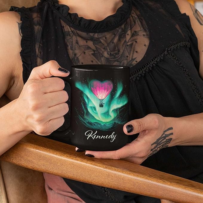 Black ceramic mug with aurora hot air balloon heart graphic and name Kennedy, held