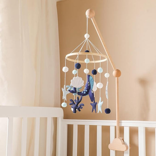 Blue whale and ocean animal crib mobile hanging from a light wood crib rail