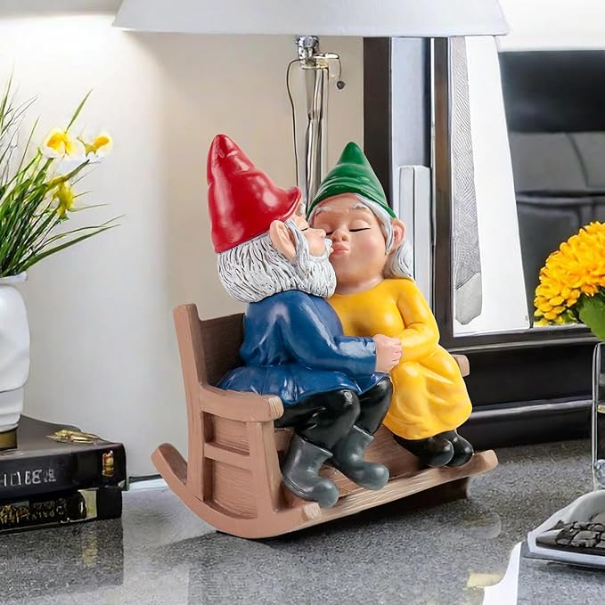 Garden gnome couple rocking chair statue on floor by window, kissing, red and green hats