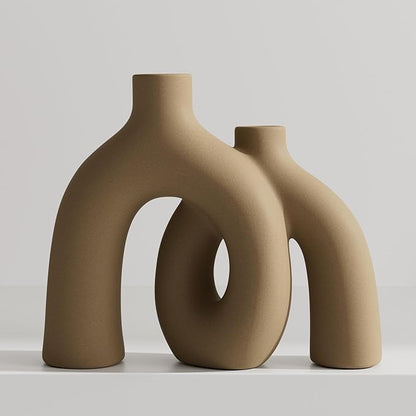 Matte tan-brown ceramic hug vase with conjoined donut sculpture, standalone.