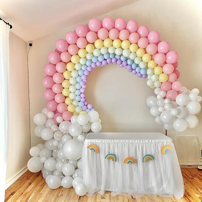 Rainbow balloon arch with pink, yellow, blue, purple, and white balloons around a white base