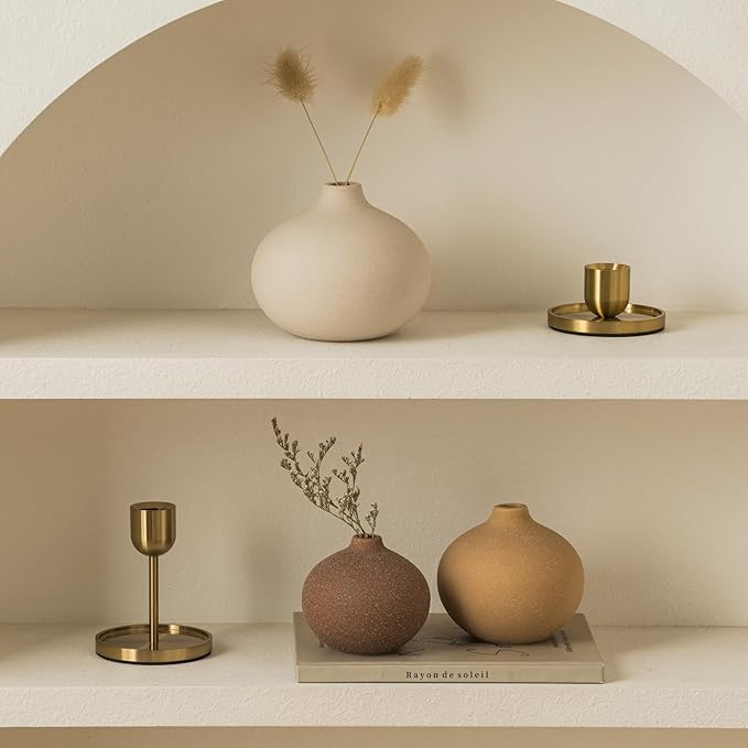 Two shelves styled with matte ceramic bud vases and dried plant stems