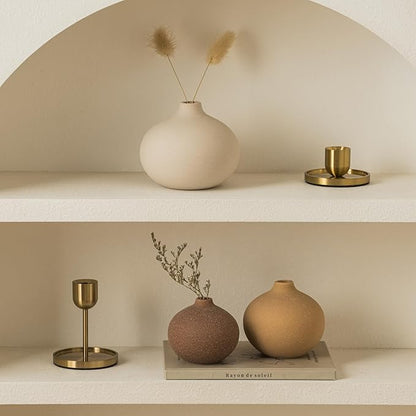 Two shelves styled with matte ceramic bud vases and dried plant stems