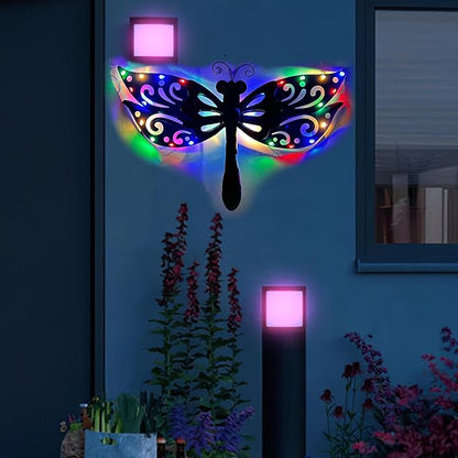 Black metal dragonfly wall art with multicolor LED wings lit at night