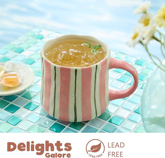 Striped ceramic coffee mug in pink with green vertical lines, filled with hot tea