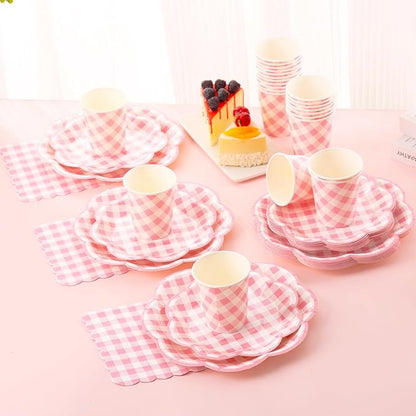 Pink gingham picnic tableware set with cups, plates, and utensils on table
