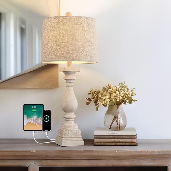 Farmhouse table lamp with beige linen shade and carved resin base, glowing light