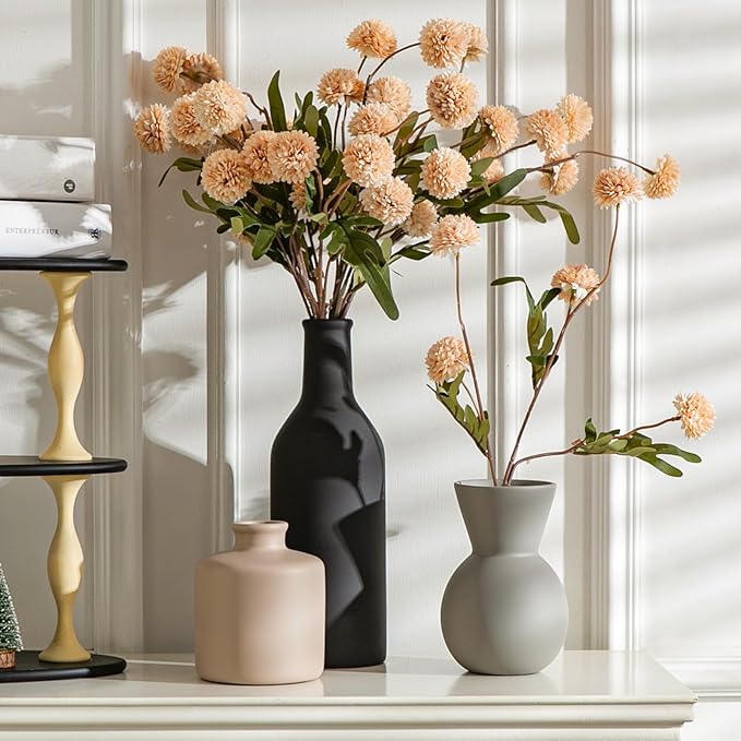 Three ceramic vases on shelf in black, white, and cream with faux chrysanthemum stems