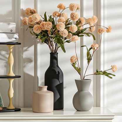 Three ceramic vases on shelf in black, white, and cream with faux chrysanthemum stems