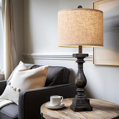 Fabric-shade table lamp with dark resin pedestal base on round side table