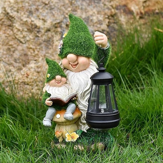 Flocked parent and child reading gnome statue holding a lit solar lantern in grass