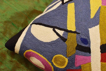 Abstract embroidered pillow cover corner with blue, yellow, and pink geometric shapes