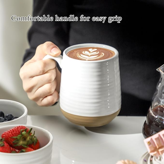 Hand holding a white ceramic coffee mug with handle and gold base ring
