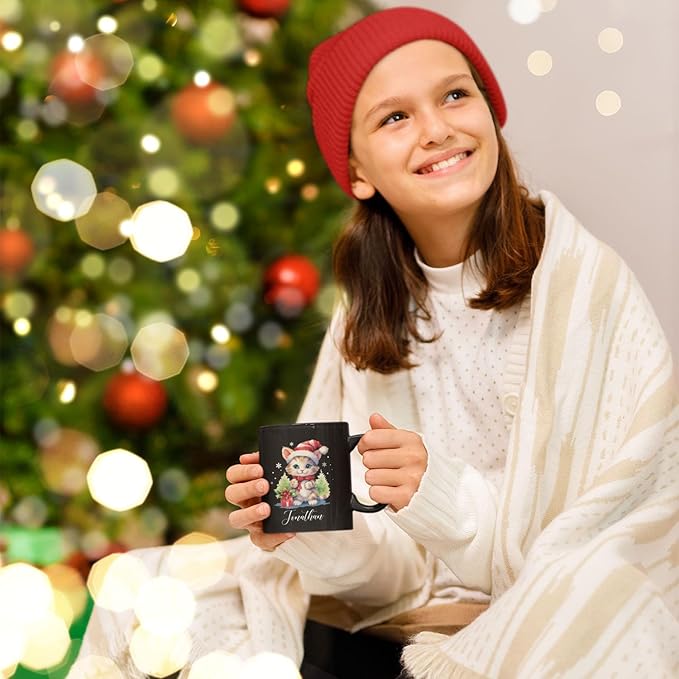 Black mug with kitten holiday print and 'Jonathan' shown in a child’s hands.