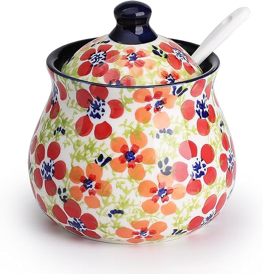 Hand-painted ceramic sugar bowl with lid and spoon, colorful floral jungle pattern.